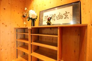 a wooden shelf with flowers and a picture on a wall at COCORETO The Guesthouse Daikon Island in Matsue