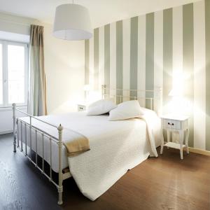 a bedroom with a white bed with striped walls at Porta Nuova Bergamo Apartments CIM123 in Bergamo