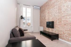 a living room with a brick wall and a tv at Weflating Ramblas in Barcelona