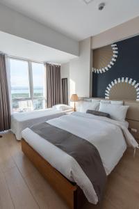a large bedroom with two beds and a large window at C Suites at Mactan Newtown in Mactan
