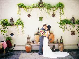 a bride and groom kissing in front of a wall at Argos Inn - Ithaca's Boutique Hotel in Ithaca
