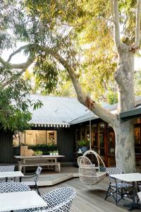 a patio with chairs and tables and a tree at Empire Spa Retreat in Dunsborough