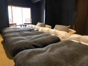 szereg poduszek na łóżku w pokoju w obiekcie Kitahama Sumiyoshi w mieście Takamatsu