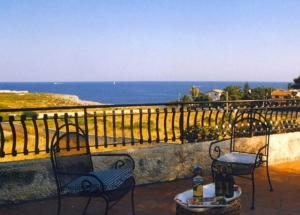 two chairs and a table on a balcony overlooking the ocean at villa smeraldi in Siracusa