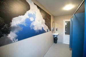 a bathroom with a painting of clouds on the wall at Hostel Sili in Mežciems
