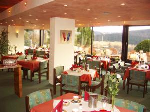 a restaurant with tables and chairs with red napkins at Wohlfühlhotel "Waldcafé Jäger" in Bad Driburg