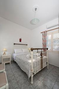 a white bedroom with a bed and a window at Giameiko Traditional House Kalymnos in Kalymnos