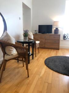 uma sala de estar com uma televisão e uma mesa e cadeiras em The Harbour Studio em Portrush