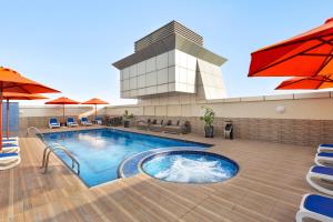 a pool with chairs and umbrellas in a building at Ramada by Wyndham Dubai Deira in Dubai