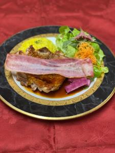 a plate of food with meat and salad on a table at Pension Fryingpan in Niseko