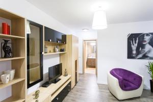 ein Wohnzimmer mit einem lila Stuhl und einem TV in der Unterkunft Unique Hotel Apartments Grand Residence in Iaşi