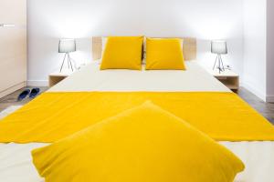 ein gelbes Bett mit zwei gelben Kissen und zwei Lampen in der Unterkunft Unique Hotel Apartments Grand Residence in Iaşi