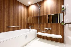 a bathroom with a white tub and wooden walls at LUXCARE HOTEL in Osaka