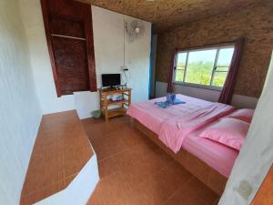 a bedroom with a pink bed and a window at Panamma Hill Resort in Khao Kho
