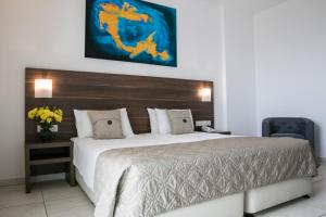 1 dormitorio con 1 cama grande y cabecero de madera en Theo Sunset Bay Hotel en Pafos