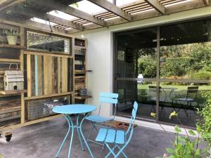 a patio with a table and two chairs and a window at The Garden Studio - Queenstown in Queenstown