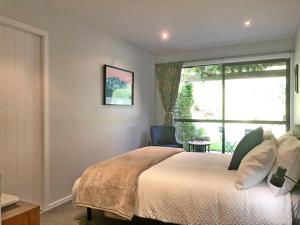 1 dormitorio con cama, ventana y silla en The Garden Studio - Queenstown en Queenstown