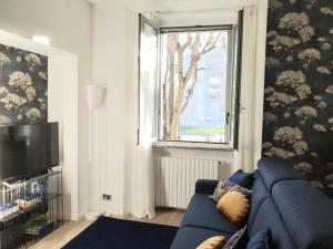 salon z niebieską kanapą i oknem w obiekcie Madeleine apartments - Arco della Pace w Mediolanie