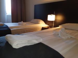 una camera d'albergo con due letti con lenzuola bianche di Ariston Hotell a Lidingö