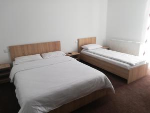 a bedroom with two beds with white sheets at Pensiune Stirbu in Borsa