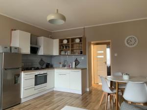 a kitchen with white cabinets and a table with chairs at Apartament „Ogrodowa” in Bolesławiec