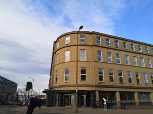 Um edifício castanho com uma mulher à frente dele. em Edinburgh Central Accommodation em Edinburgo
