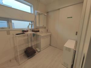 a small white bathroom with a sink and a window at Private House Naturwald in Furano