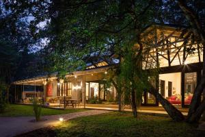 uma casa com uma árvore em frente em Mbano Manor Hotel Victoria Falls by Mantis em Victoria Falls
