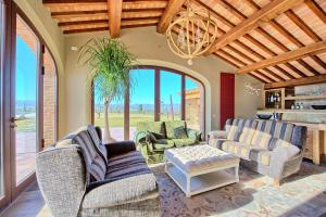 een woonkamer met banken en stoelen en een kroonluchter bij Villa Massimiliano by PosarelliVillas in Volterra