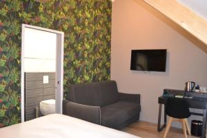 a living room with a chair and a television at Logis Auberge de Pont Calleck in Inguiniel