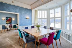 Hotel Villa Hügel في ترير: غرفة طعام مع طاولة خشبية وكراسي ملونة
