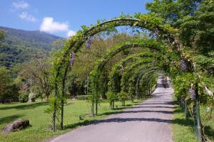 an archway with purple flowers on a road at Butterfly Valley Resort in Ruisui