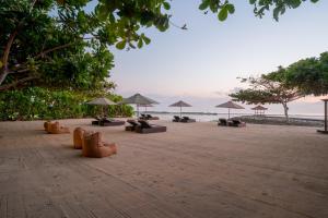 een zandstrand met parasols en stoelen en de oceaan bij Kayumanis Nusa Dua Private Villa & Spa in Nusa Dua