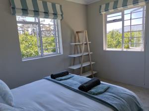 a bedroom with a bed with two windows and a ladder at Moortop Cottages in Elgin