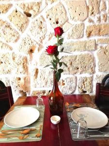 una mesa con platos y un jarrón con una rosa. en Suite Sant'Irene, en Veglie