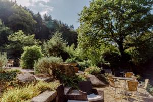 un patio con sillas y mesas en un jardín en Logis Auberge de Pont Calleck, en Inguiniel