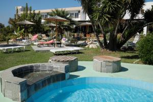 a beach with a pool, chairs, and a pool table at Rhodian Sun Hotel in Paradeísion