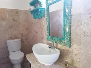 a bathroom with a white toilet and a mirror at Puri Oka Beach Bungalows in Candidasa