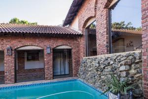 a brick house with a swimming pool next to a building at Stephan's Guest House in Port Shepstone