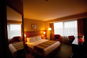 a hotel room with a bed and two windows at VILNIUS PARK PLAZA HOTEL, Restaurant & Terrace, Panorama Bar, Conference & Banquet Center in Vilnius