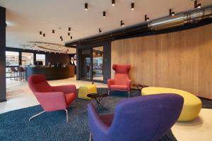 eine Lobby mit bunten Stühlen und Tischen in einem Gebäude in der Unterkunft Hotel im LESKANPark in Köln
