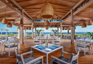 un restaurante en la playa con mesas y sillas en Jaz Maraya Resort en Coraya Bay