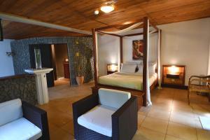 1 dormitorio con cama con dosel y silla en TAPACALA INSOLITE en Cilaos