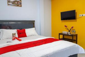 een slaapkamer met een rood en wit bed en een televisie bij RedDoorz near RSUD Kota Luwuk in Luwuk