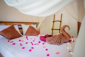Una cama con pétalos de flores rosas. en Jati Village, Party Hostel and Bungalows, en Gili Trawangan