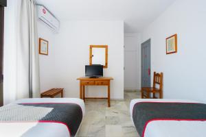 
a room with a bed, desk, chair and a television at Hotel El Ancla in Calahonda
