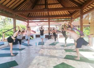 a group of people doing yoga in a pavilion at Puri Oka Beach Bungalows in Candidasa