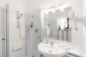 a white bathroom with a sink and a shower at Hotel Villa Groff in Ora/Auer