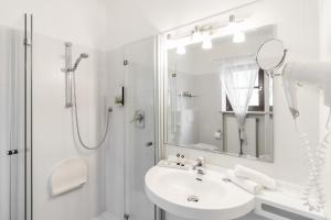 La salle de bains blanche est pourvue d'un lavabo et d'une douche. dans l'établissement Hotel Villa Groff, à Ora
