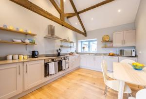 a large kitchen with white cabinets and a table at Stapleford Farm Cottages in Beaminster